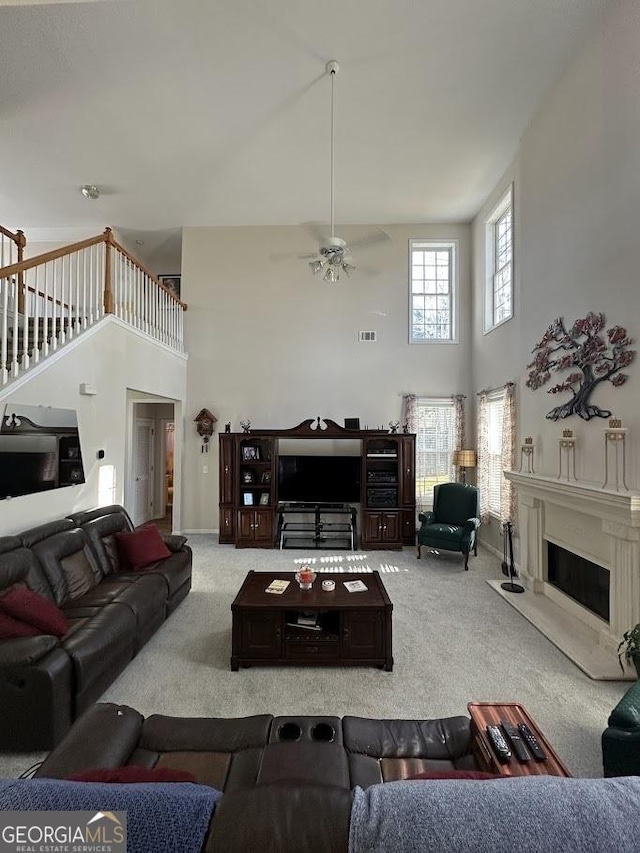 living room with stairs, carpet, a towering ceiling, and a premium fireplace