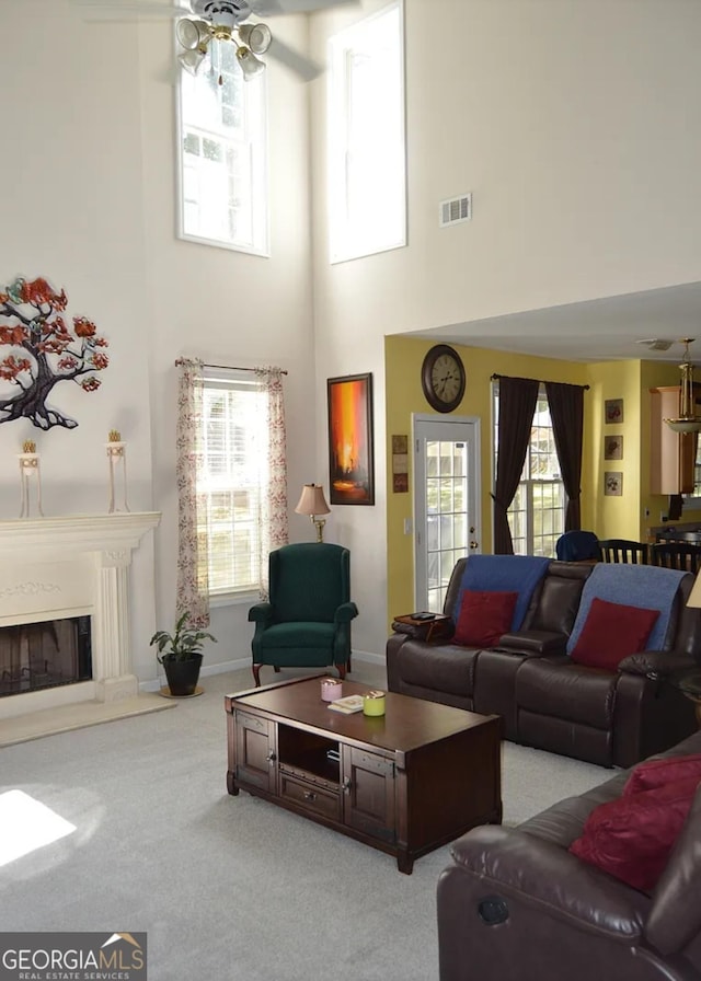 living area with baseboards, visible vents, a glass covered fireplace, ceiling fan, and carpet floors