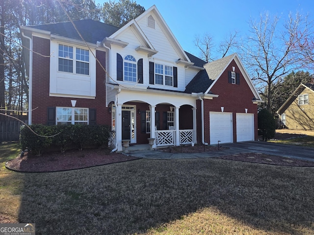 traditional home with a garage, driveway, a porch, and brick siding