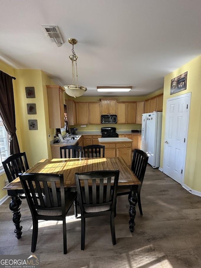 dining area featuring dark wood-style flooring, visible vents, and baseboards