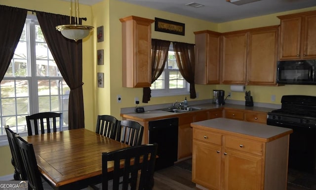 kitchen featuring a kitchen island, a sink, visible vents, light countertops, and black appliances