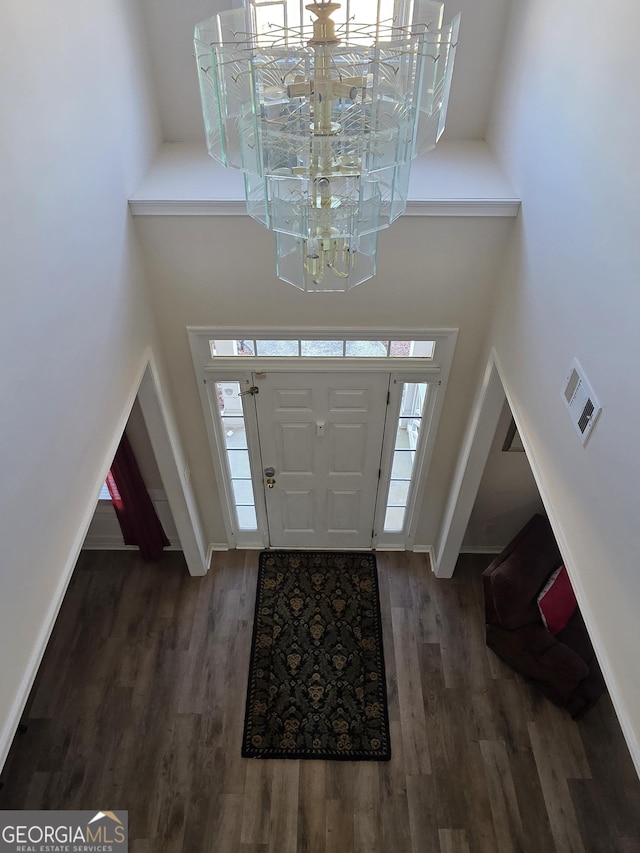 entryway with a towering ceiling, baseboards, and wood finished floors