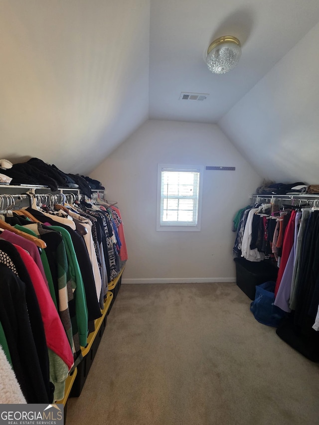 walk in closet with carpet floors, lofted ceiling, and visible vents