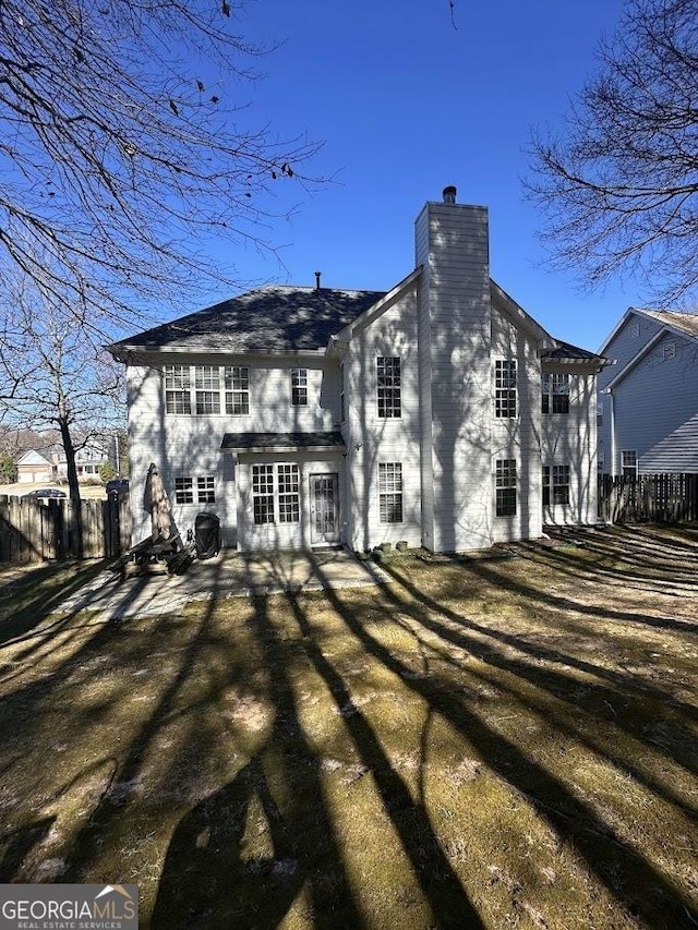 back of house with fence and a chimney