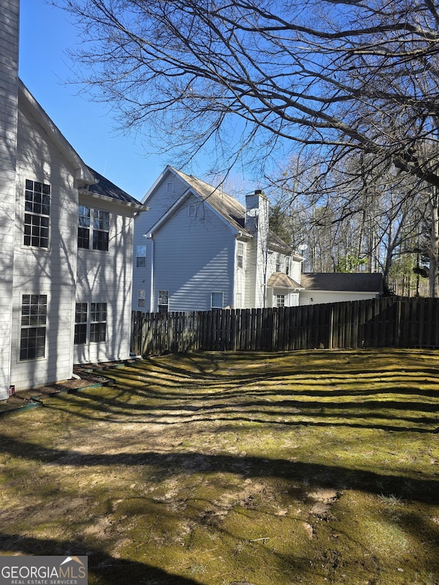 view of side of home with fence and a yard