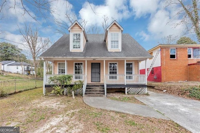 new england style home with a porch, roof with shingles, and fence