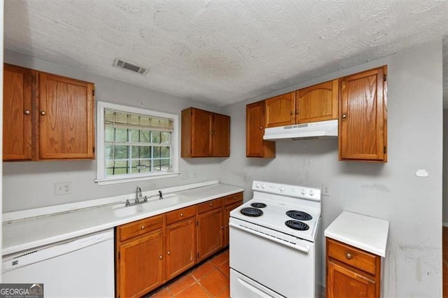 kitchen featuring visible vents, brown cabinetry, a sink, white appliances, and under cabinet range hood