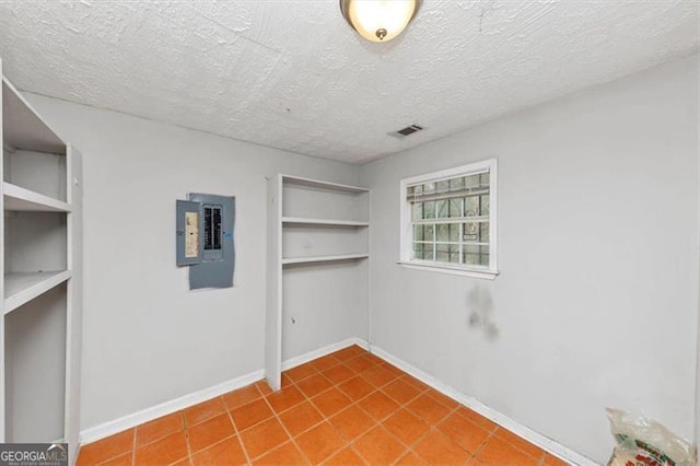 spare room featuring a textured ceiling, electric panel, and baseboards