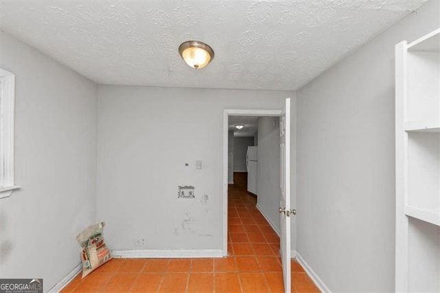 spare room with light tile patterned floors, baseboards, and a textured ceiling