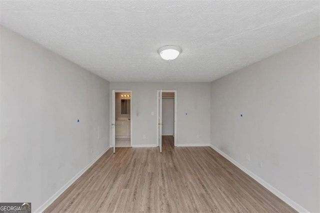 spare room with a textured ceiling, baseboards, and wood finished floors