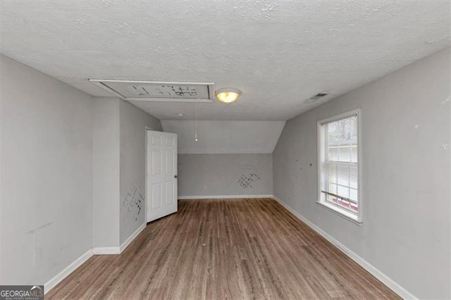 additional living space featuring wood finished floors, attic access, and baseboards