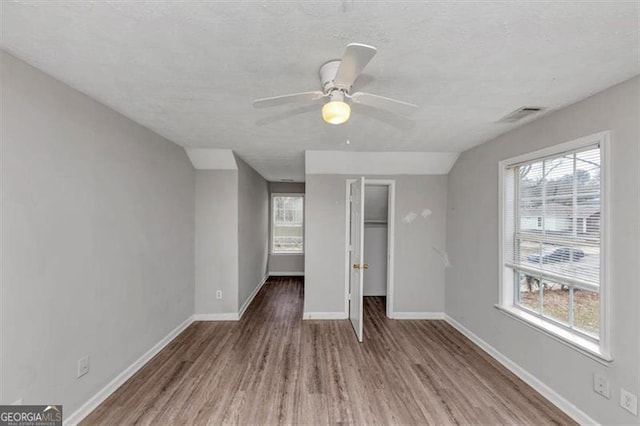 unfurnished bedroom with a closet, visible vents, ceiling fan, wood finished floors, and baseboards