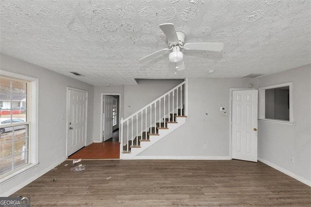 entryway featuring baseboards, visible vents, stairway, wood finished floors, and a textured ceiling