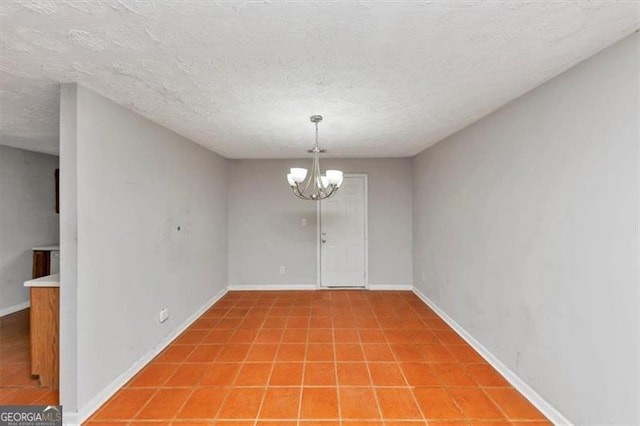 spare room featuring a textured ceiling, baseboards, a notable chandelier, and light tile patterned flooring