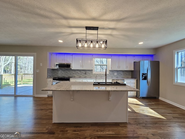 kitchen featuring dark wood-type flooring, stainless steel appliances, backsplash, and a center island