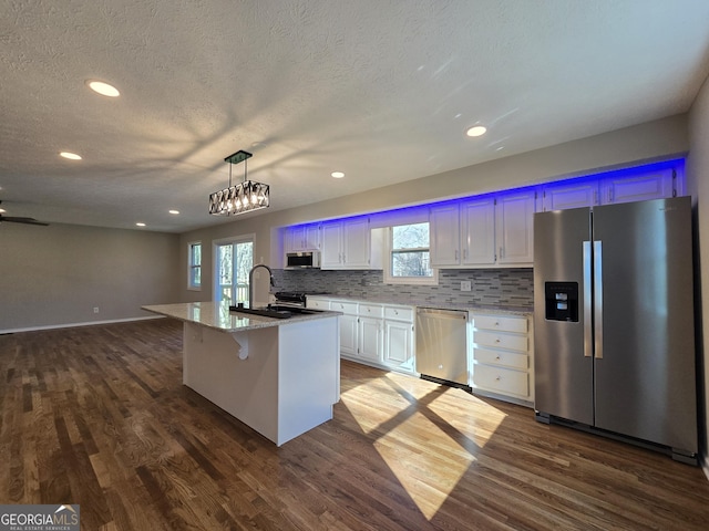 kitchen featuring dark wood-style floors, stainless steel appliances, backsplash, and a healthy amount of sunlight