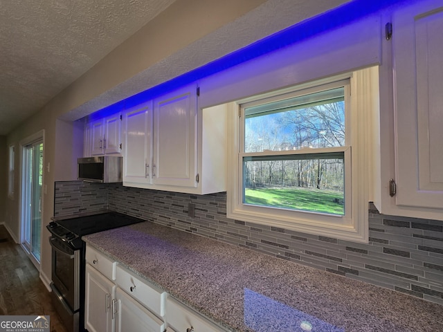 kitchen with a textured ceiling, stainless steel appliances, backsplash, and white cabinets