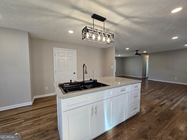 kitchen featuring open floor plan, dark wood-type flooring, white cabinetry, a sink, and recessed lighting