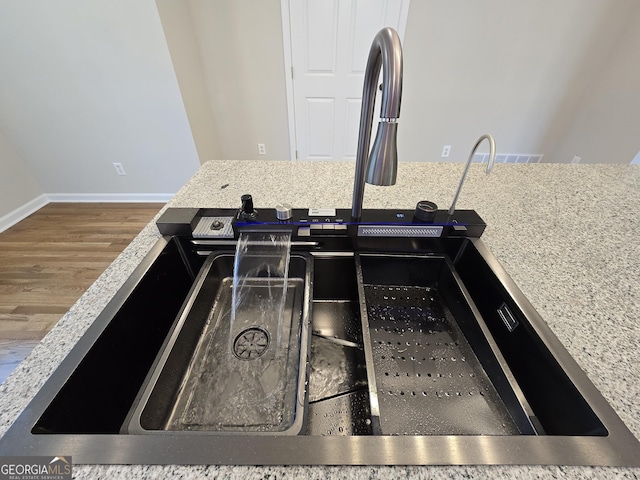 room details featuring wood finished floors, a sink, and baseboards