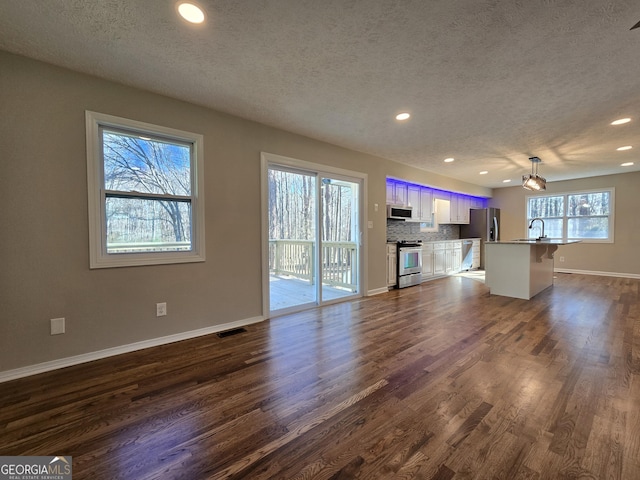 unfurnished living room featuring baseboards, visible vents, dark wood-style floors, a sink, and recessed lighting