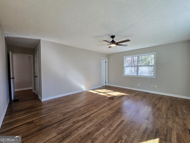 unfurnished room with a textured ceiling, ceiling fan, dark wood-style flooring, and baseboards