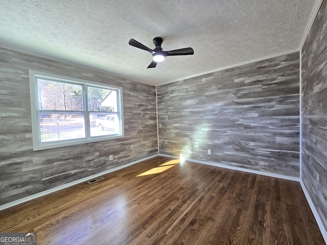 spare room with visible vents, a textured ceiling, baseboards, and wood finished floors