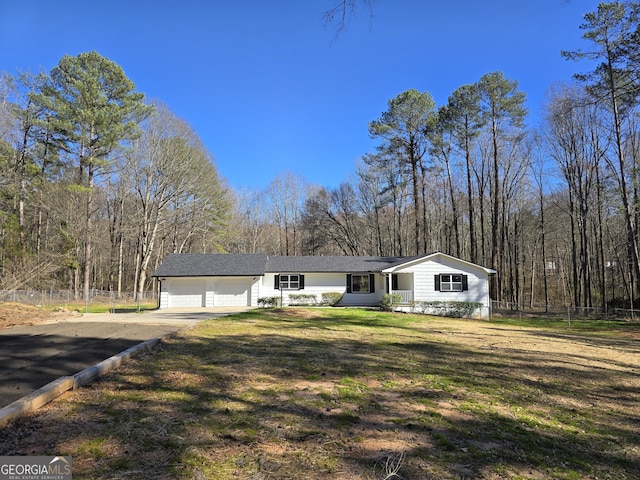 view of front of property featuring concrete driveway, a front lawn, an attached garage, and fence