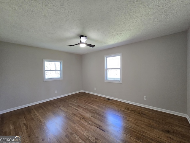 unfurnished room with dark wood-style flooring, a wealth of natural light, and baseboards