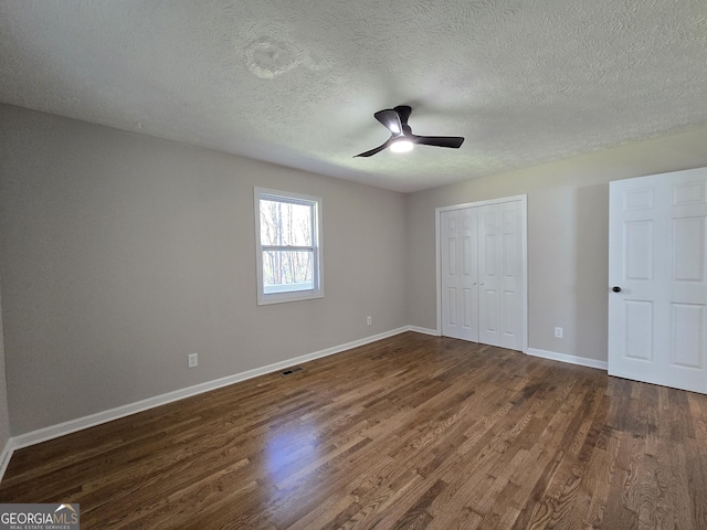 unfurnished bedroom featuring baseboards, a closet, visible vents, and dark wood-style flooring