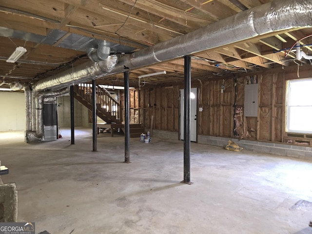 basement featuring electric panel and heating unit