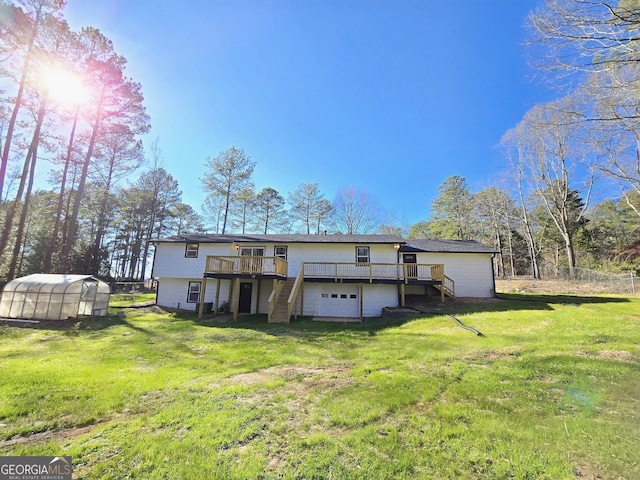 rear view of property with a lawn, a greenhouse, an outbuilding, stairs, and a deck