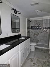 full bathroom featuring double vanity, a stall shower, a sink, and toilet