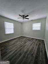 empty room featuring ceiling fan, wood finished floors, and baseboards