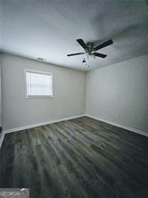 spare room with wood finished floors, a ceiling fan, and baseboards