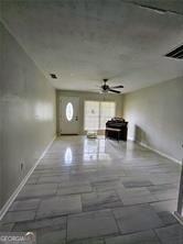 unfurnished living room with ceiling fan and baseboards