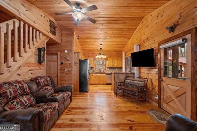 living room featuring wooden ceiling, ceiling fan with notable chandelier, wood walls, light wood-style floors, and vaulted ceiling