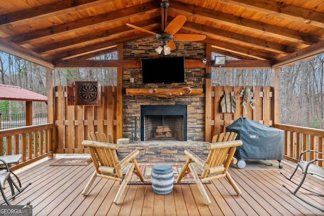 wooden terrace with an outdoor stone fireplace, fence, area for grilling, and ceiling fan