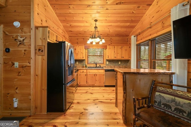 kitchen with lofted ceiling, light brown cabinets, stainless steel appliances, and a peninsula