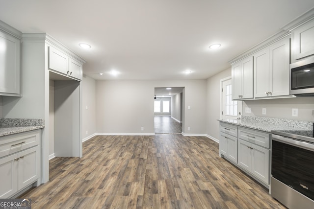 kitchen with baseboards, dark wood-style floors, light stone counters, stainless steel appliances, and recessed lighting