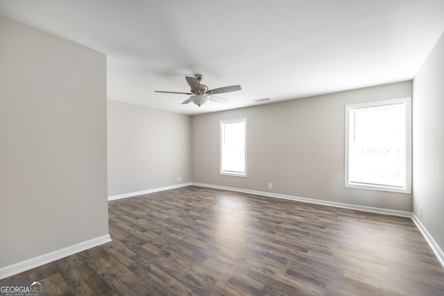 unfurnished room featuring dark wood-style floors, visible vents, and baseboards