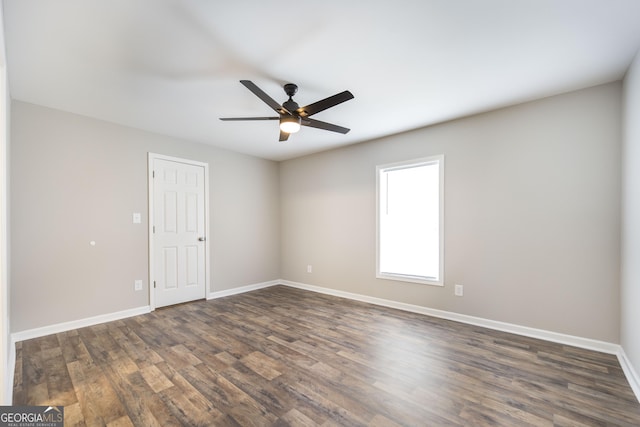 spare room featuring baseboards, dark wood finished floors, and a ceiling fan