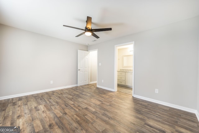 unfurnished bedroom featuring ceiling fan, ensuite bath, wood finished floors, and baseboards