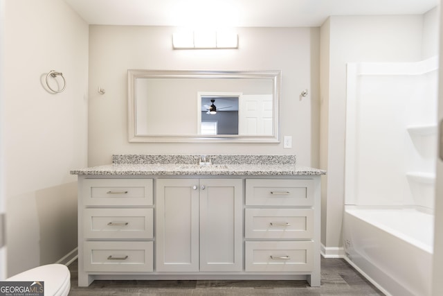 full bath with wood finished floors, vanity, toilet, and baseboards