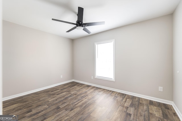 spare room featuring dark wood-style flooring, ceiling fan, and baseboards