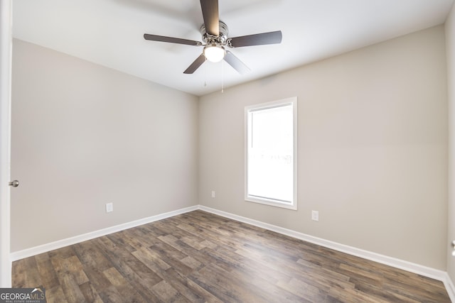 empty room featuring dark wood finished floors, a ceiling fan, and baseboards