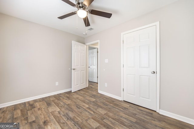 unfurnished bedroom featuring a ceiling fan, baseboards, visible vents, and wood finished floors