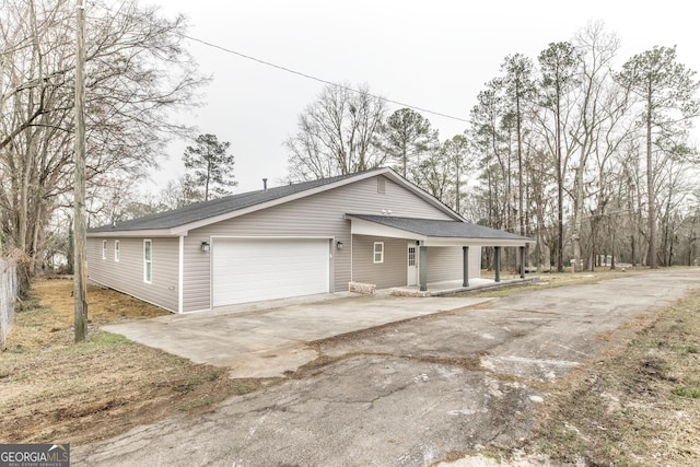 view of front facade with a porch, driveway, a shingled roof, and a garage