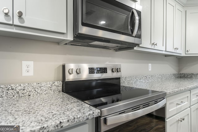 kitchen featuring appliances with stainless steel finishes, wood finished floors, white cabinetry, and light stone countertops