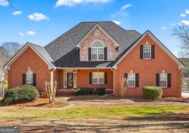 traditional-style house with roof with shingles, brick siding, and a front lawn