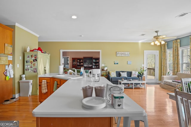 kitchen featuring open floor plan, light wood-style flooring, visible vents, and crown molding